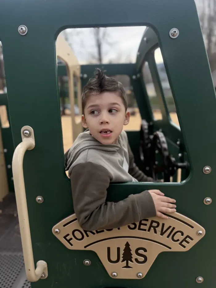The original snapshot: the same boy climbing on a green Forest Service playground truck